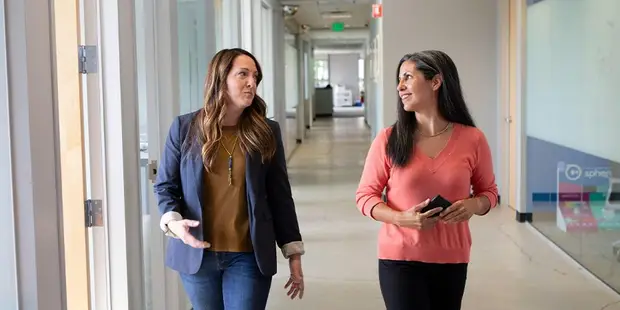 Two AFX Research colleagues walking and talking in an office corridor while discussing a property research file